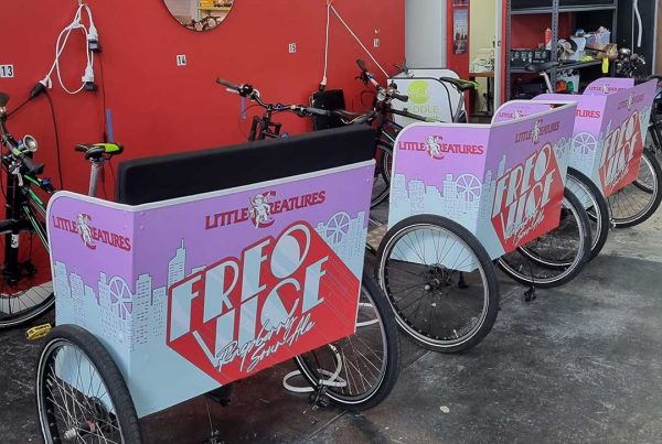 Three bicycle carriages with purple vinyl stickers applied to the carriage body
